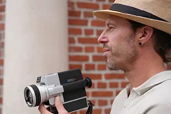 Matthieu De Waele, zaakvoerder van Ecomoda-Video, met een Super 8 camera in de hand — symbool voor persoonlijk contact en vakmanschap.